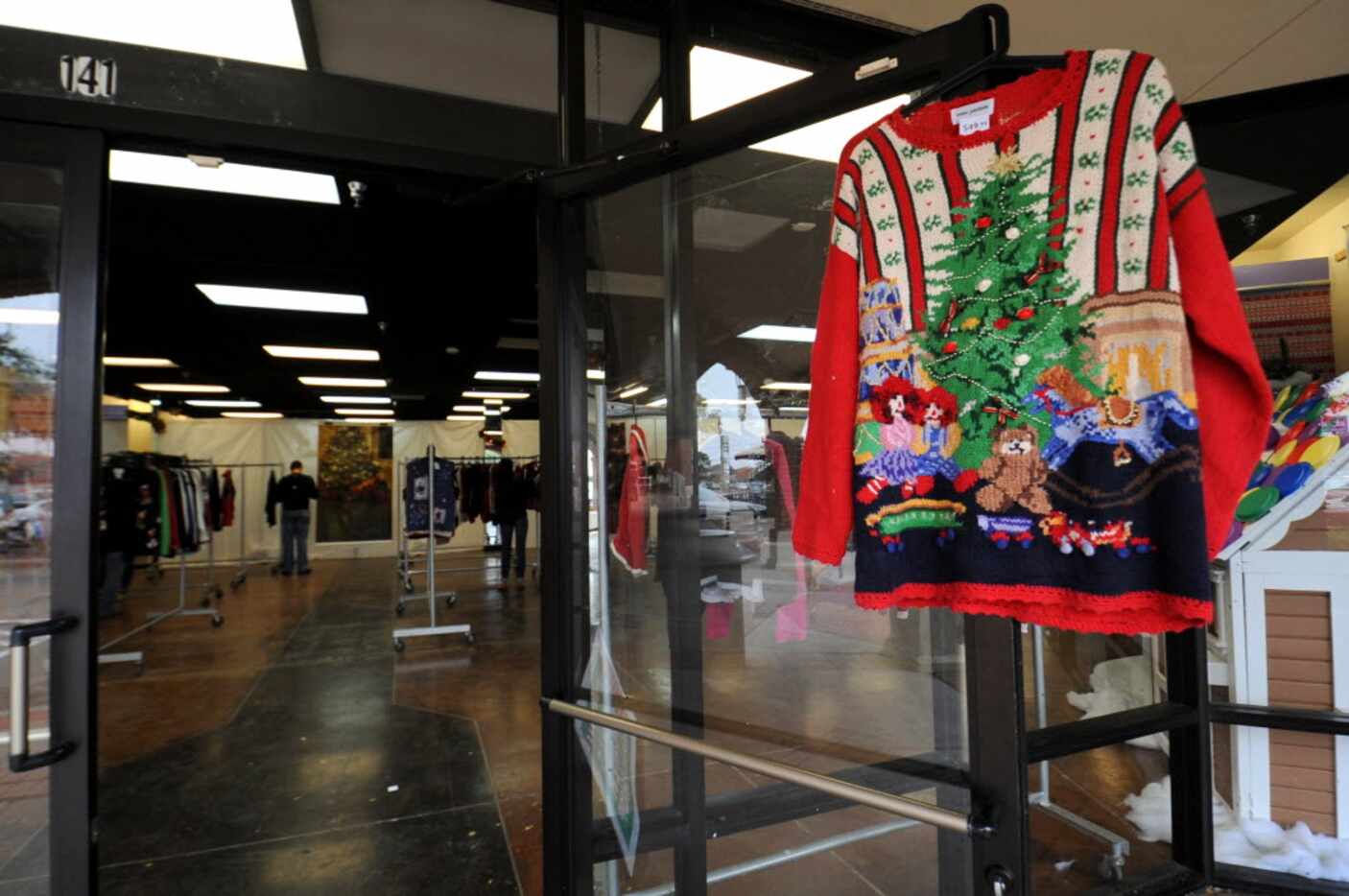 An ugly sweater hangs on the door giving customers a taste of one of hundreds of sweaters...