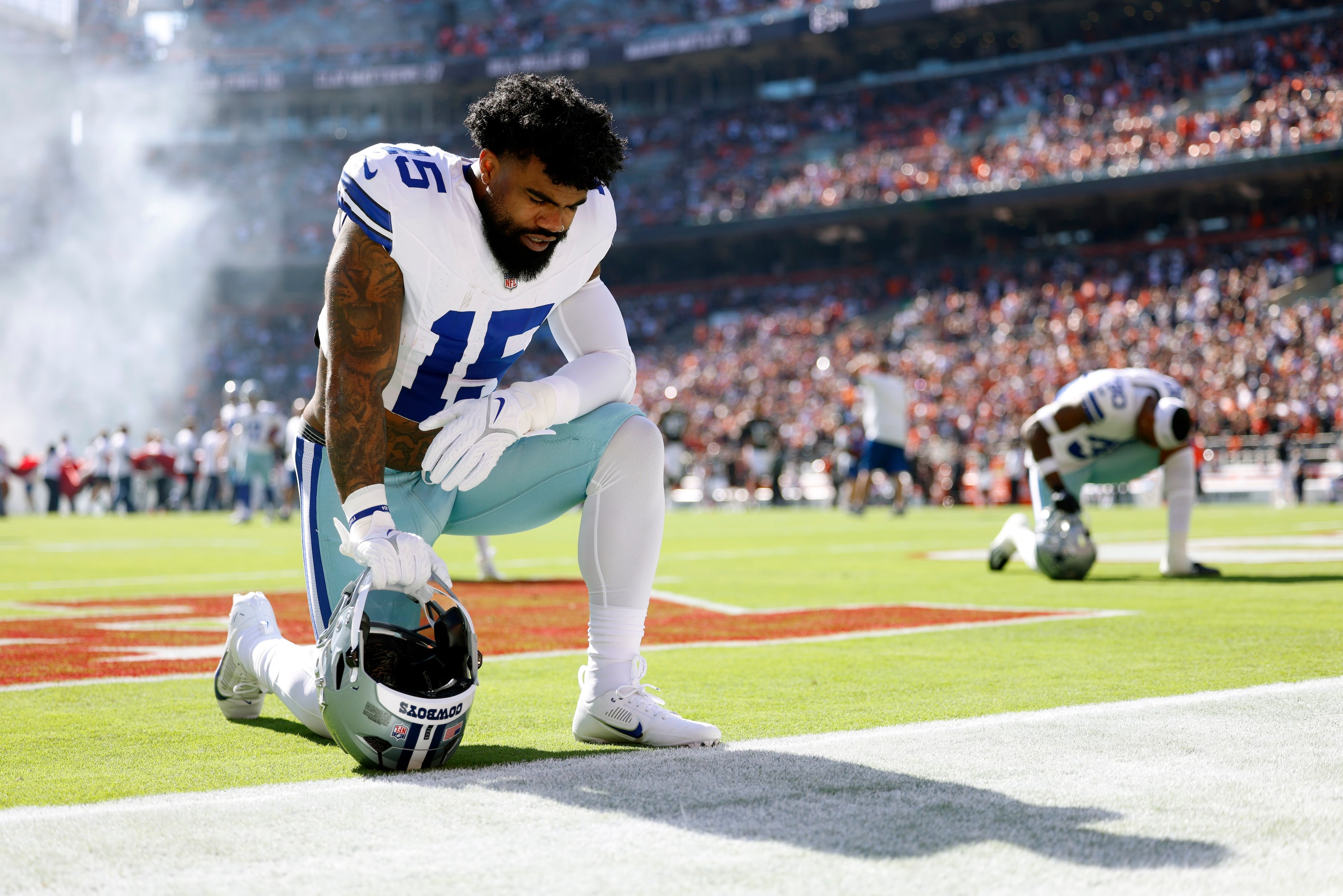 Dallas Cowboys running back Ezekiel Elliott (15) kneels in the end zone before a game...