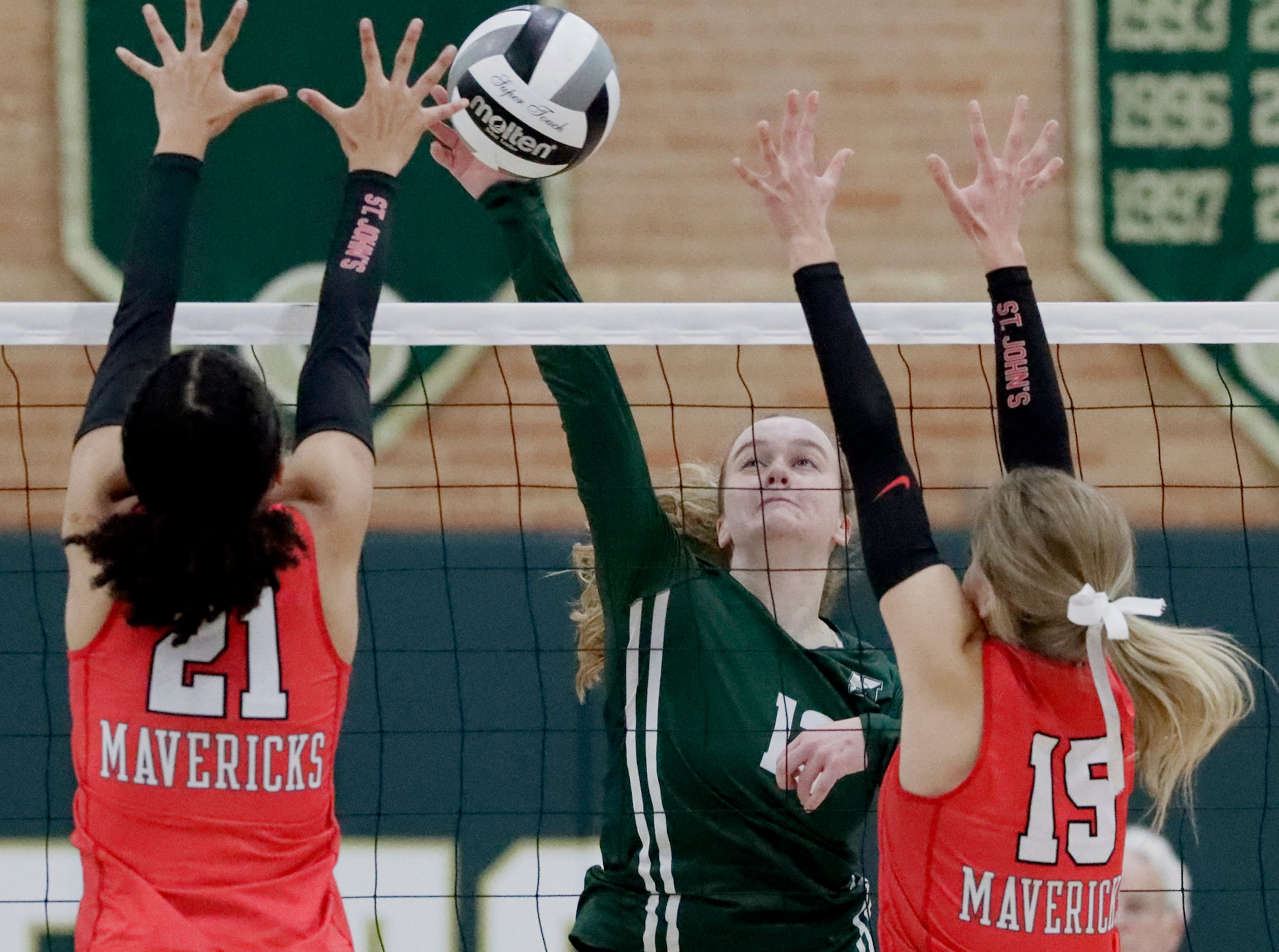 Hockaday middle blocker Zoe Heintges (13) gets a hit between St. John's middle Caroline...