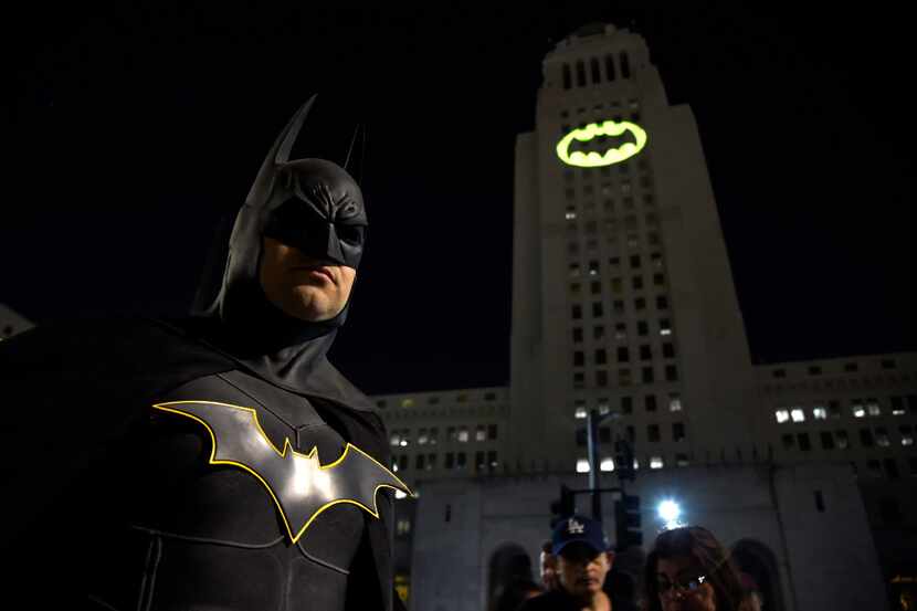 Tony Bradshaw, of Los Angeles, dressed as Batman, poses in front of a Bat-Signal projected...
