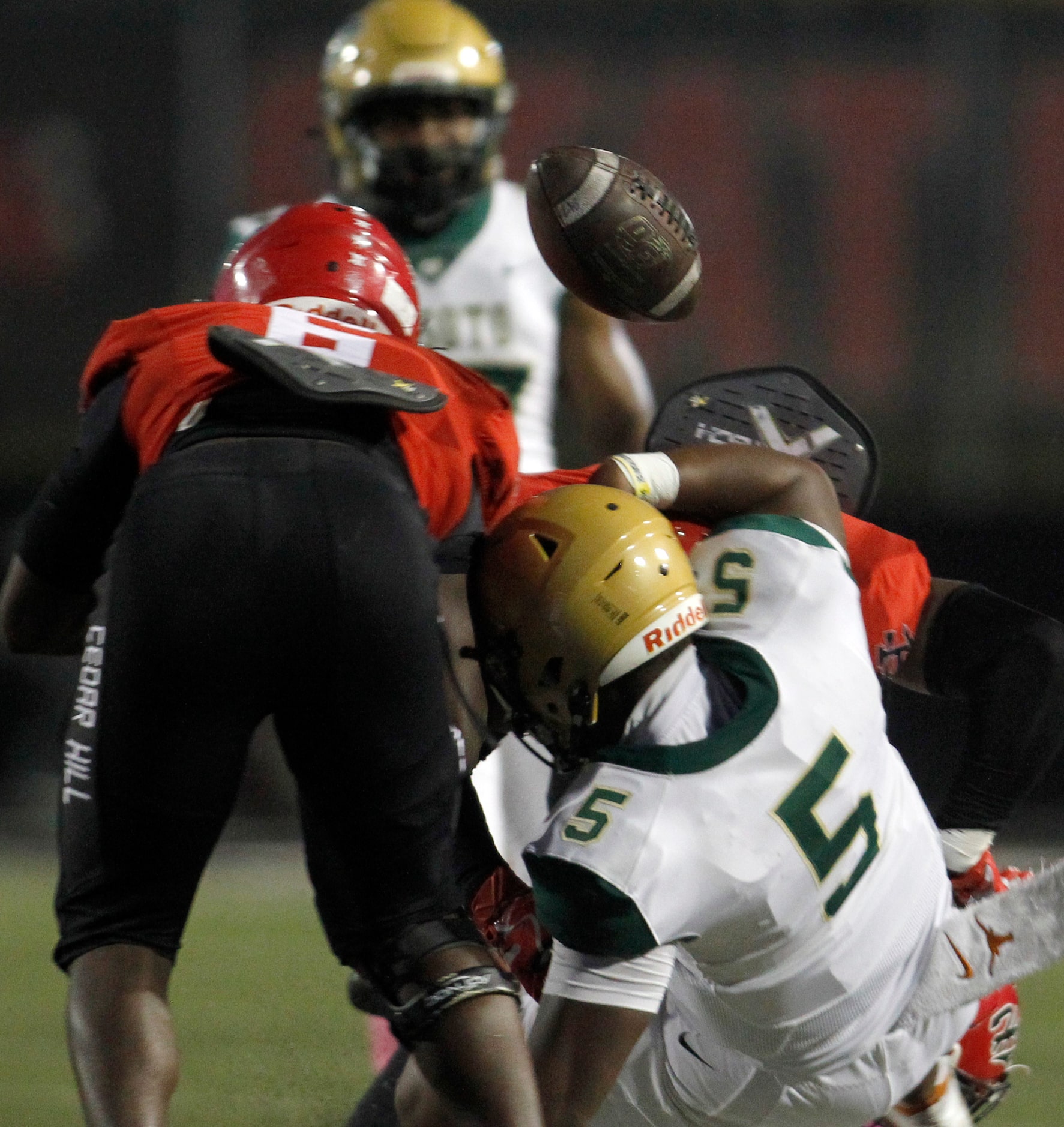 DeSoto quarterback Darius Bailey (5) fumbles the ball after a hit by a Cedar Hill defender...