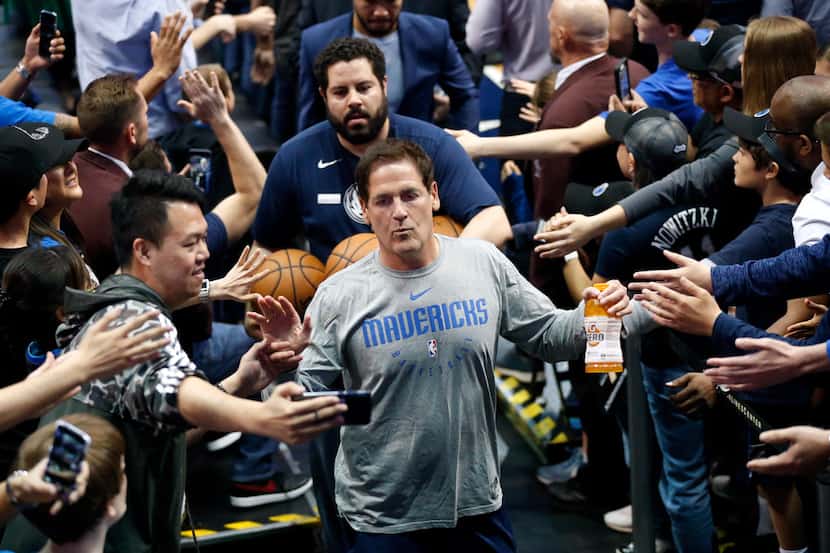 Dallas Mavericks owner Mark Cuban slaps hands with fans as he leaves the court following...