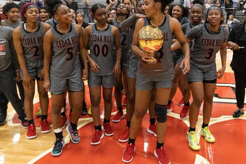 Cedar Hill players look a their teammate Micah Vaughn (33) while she holds a trophy at...