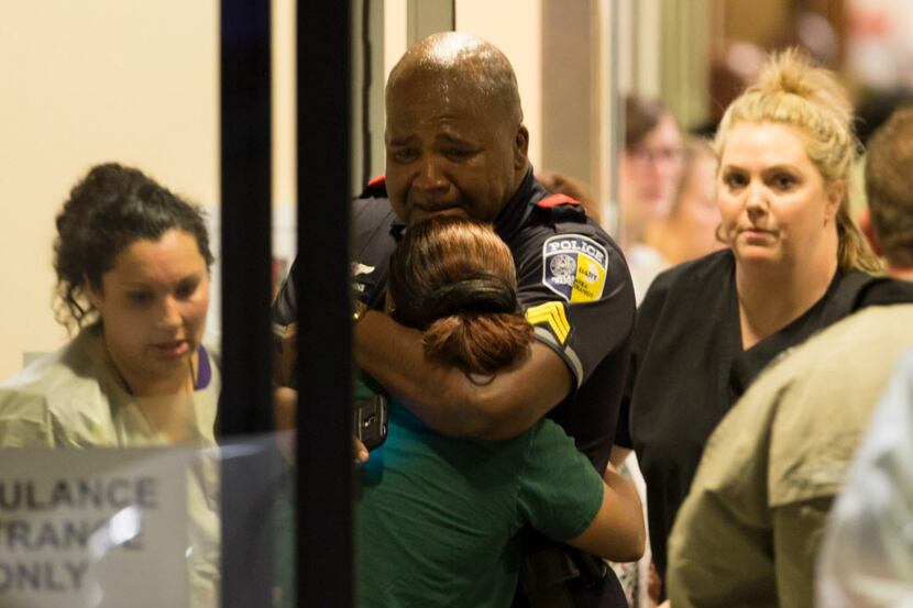 A DART police officer receives comfort at Baylor University Hospital emergency room entrance...