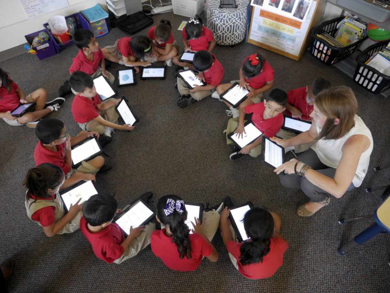 Momentous School of Dallas kindergartners form a circle to look at the new tablets they...