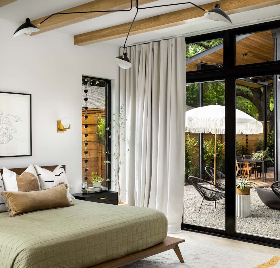 Interior home bedroom with sliding glass doors leading out to a patio seating area.
