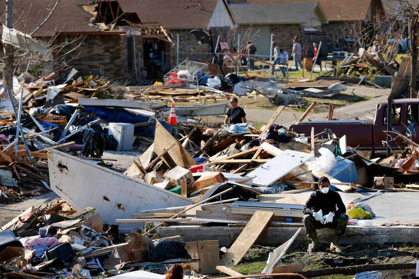 A volunteer took a break from cleaning away debris from a tornado-ravaged home in Garland on...