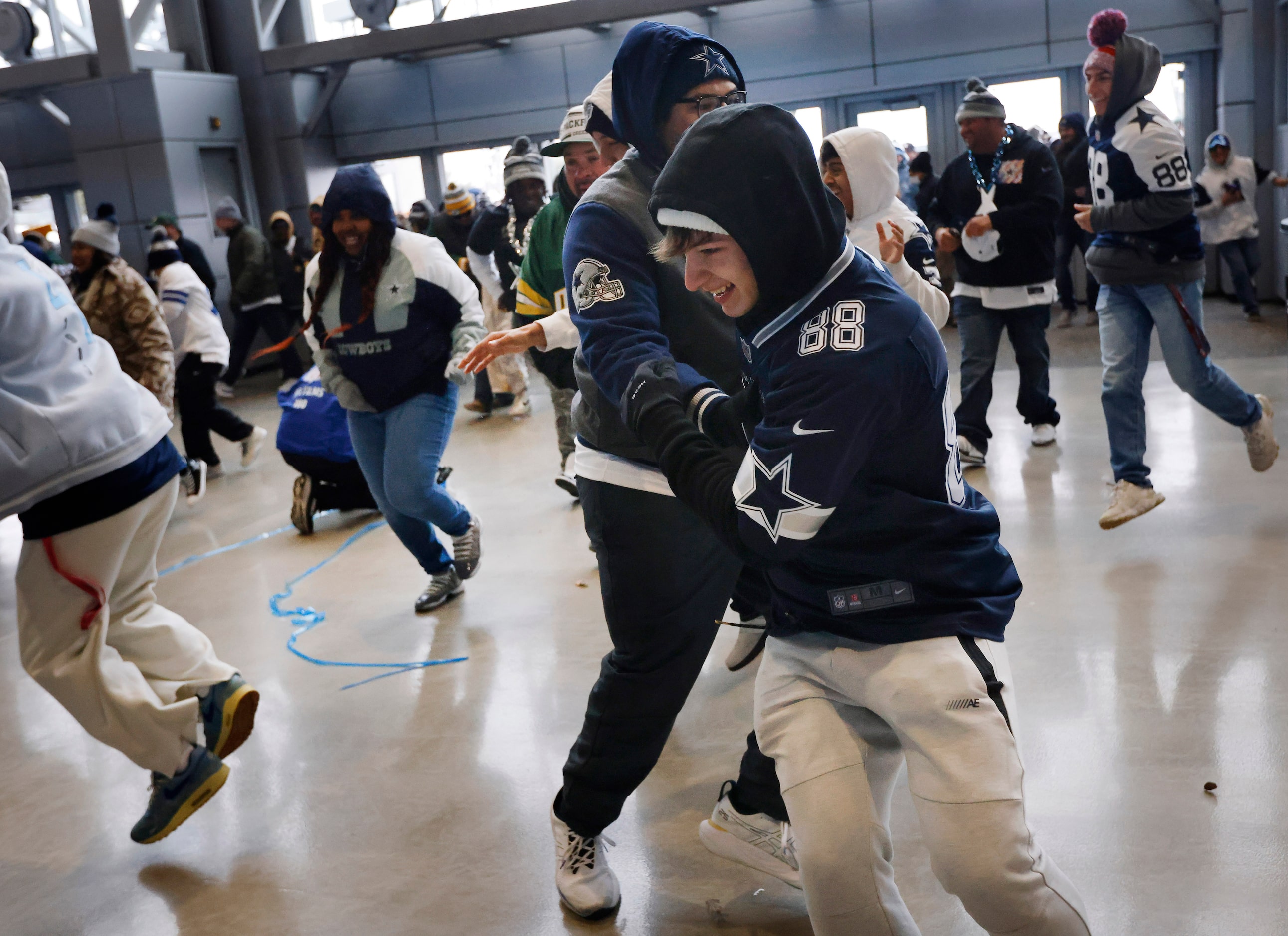 A pair of Dallas Cowboys fans collide as they race through the west plaza doors in hopes of...