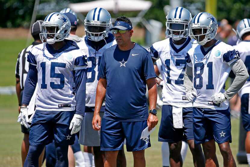 Dallas Cowboys wide receiver coach Sanjay Lal, center, is surrounded by his players Deonte...