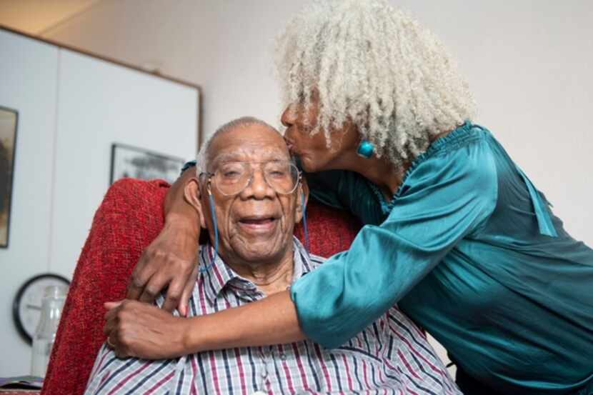 A senior woman gives her 91-year old father a kiss on the head.