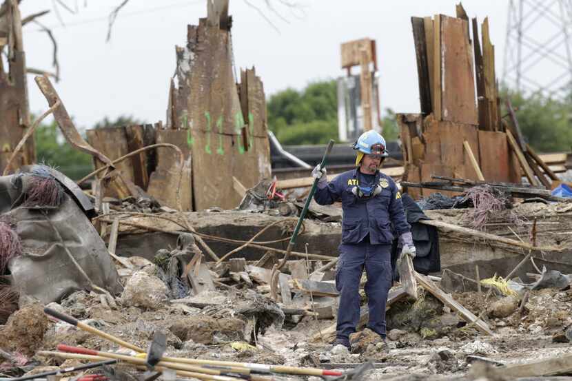 An investigator pauses while sifting through the debris of the destroyed fertilizer plant in...