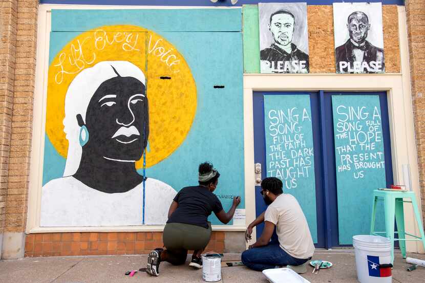 Desiree Vaniecia and Joeneal Berry sign their names on a mural they painted on plywood on...