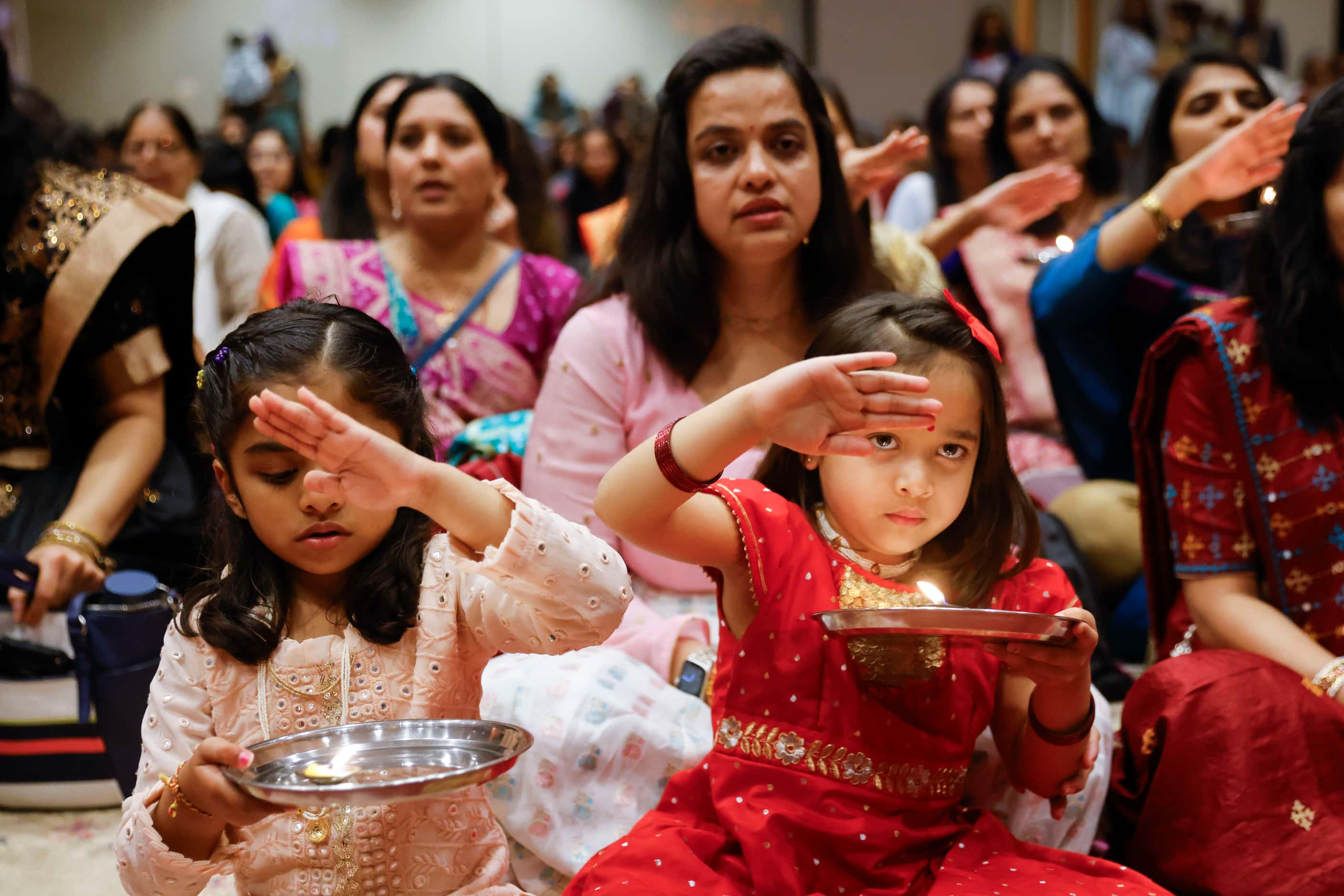 Katha Patel, 5, (left) and Akshara Patel, 5, gesture as they take part in a Jayanti during a...