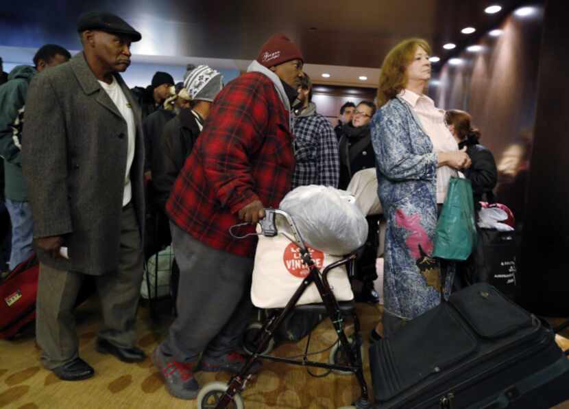 Carol 'Mama' Hawkins, 58, (center) waits in line to receive a backpack and clothes with...