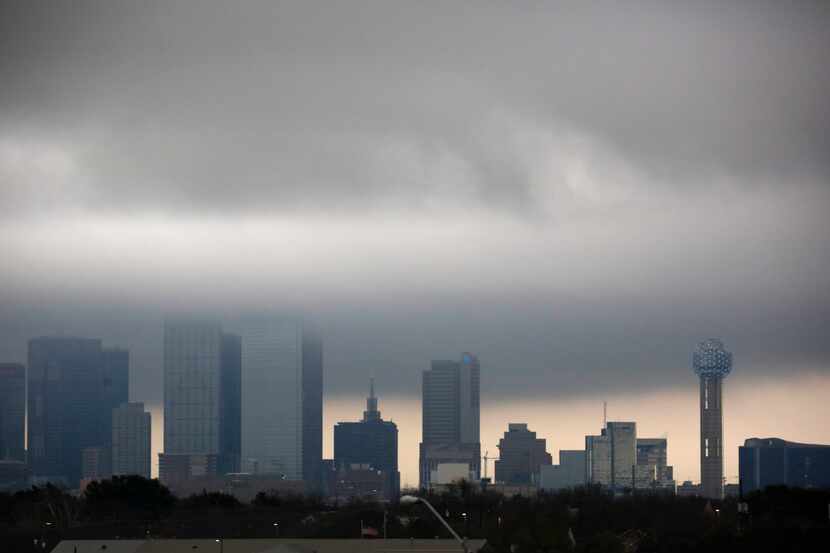 Low clouds developing along the cold front pass through buildings in downtown Dallas,...