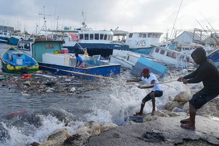 Fishermen pull a boat damaged by Hurricane Beryl back to the dock at the Bridgetown...