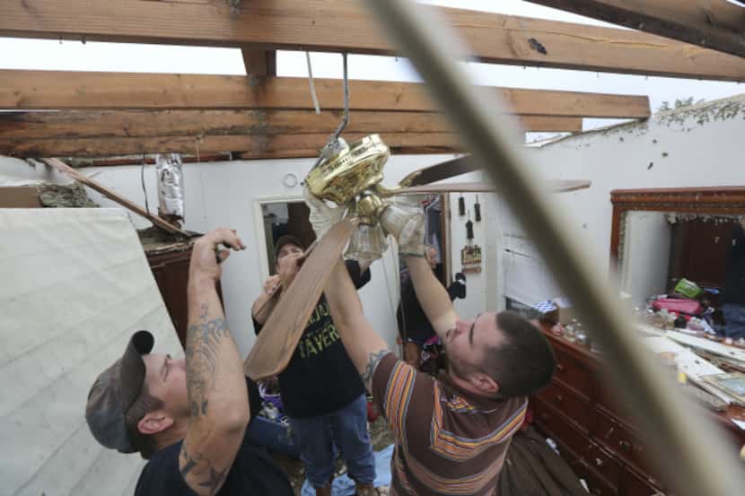 Derrek Grisham (right), Jeremy Hulce (left) and Dustin Seay cut down a fan without a ceiling...