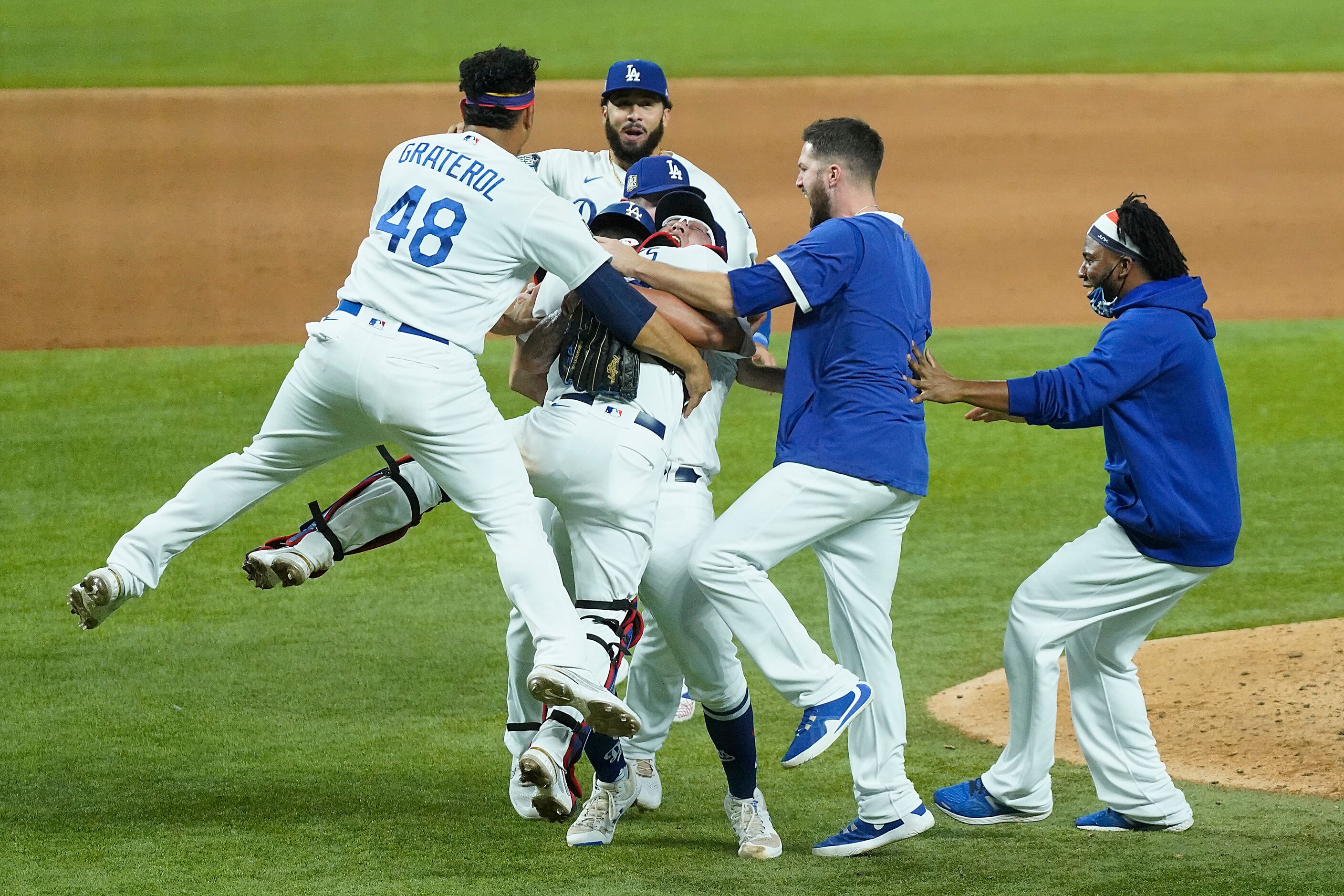 Los Angeles Dodgers players rush to join pitcher Julio Urias and catcher Austin Barnes as...