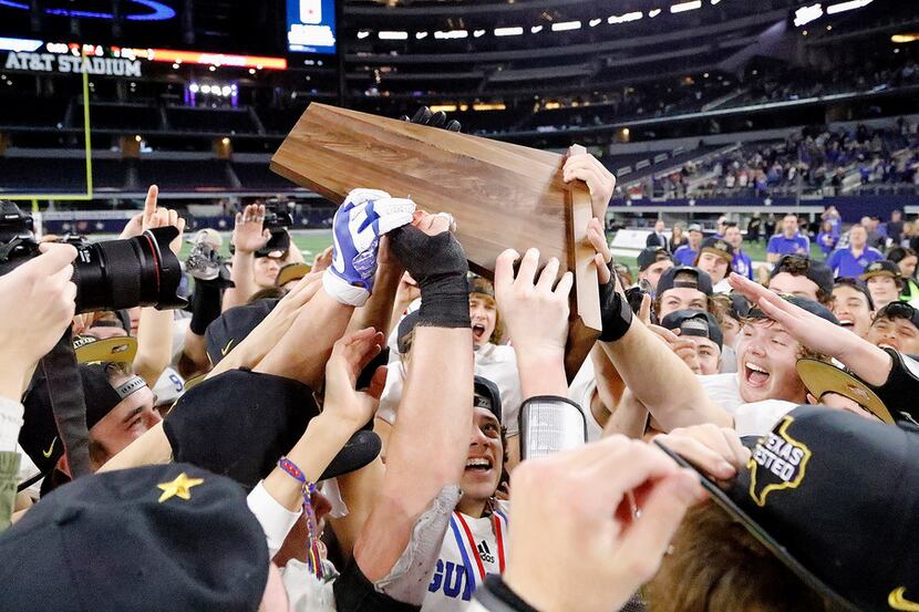 The Gunter High School football team celebrates with the championship trophy after their...