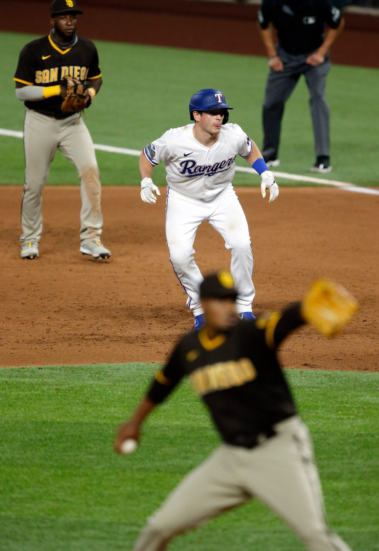 Texas Rangers Nick Solak (center) takes a lead off first as San Diego Padres relief pitcher...