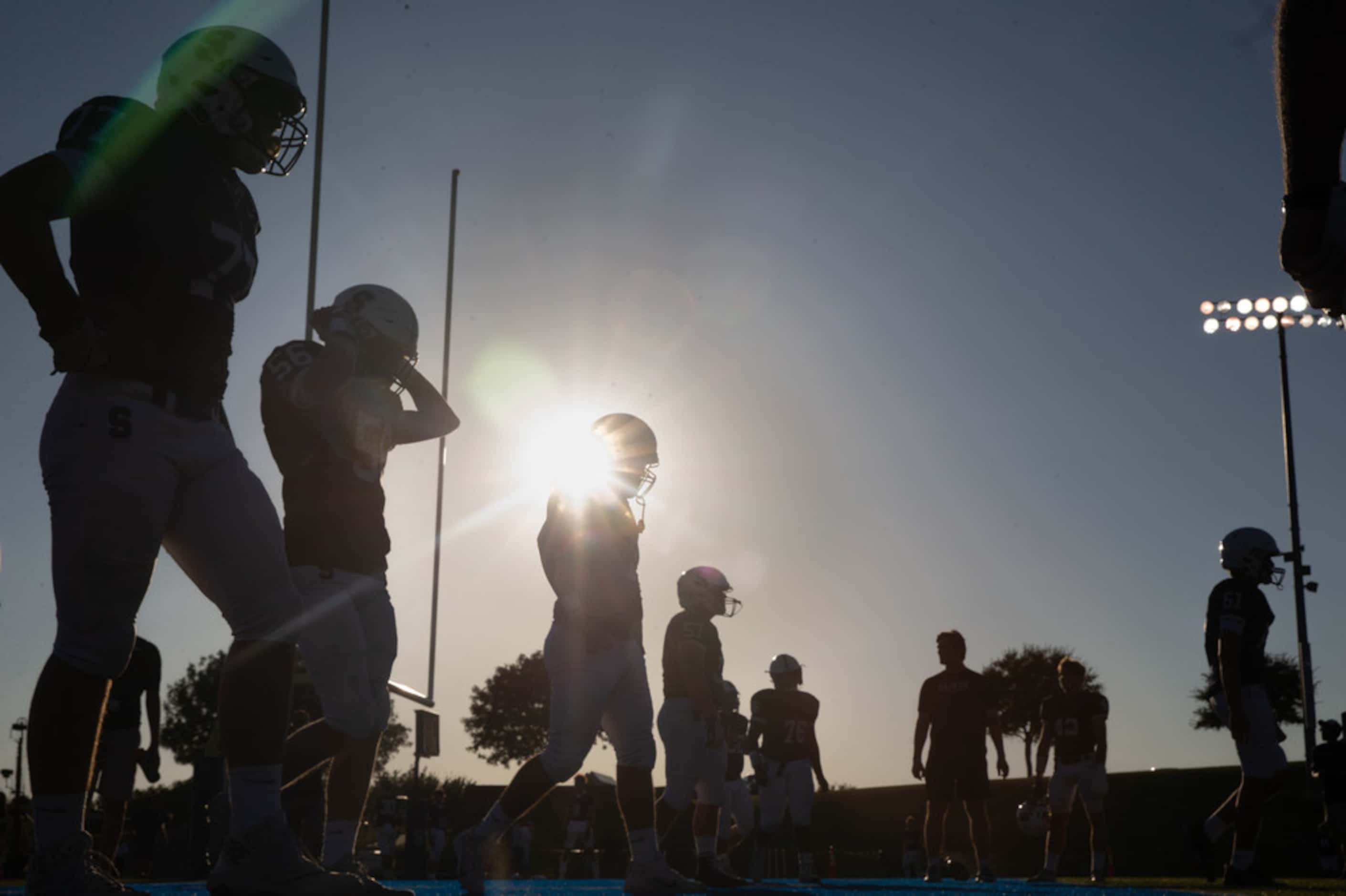 The sun begins to set behind the All Saints' Episcopal School varsity football team as they...