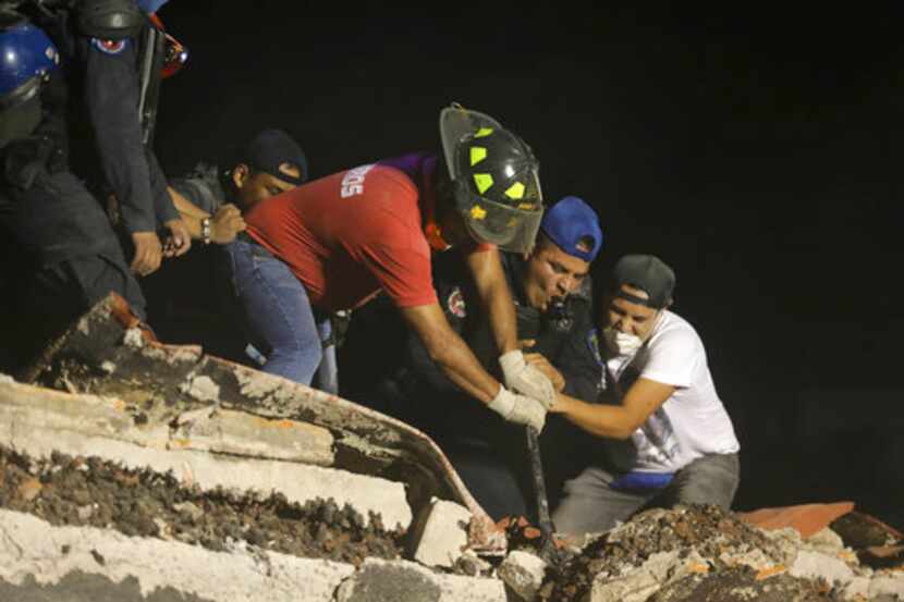 Rescatistas y voluntarios buscan en un edificio derrumbado tras un sismo en el barrio de...