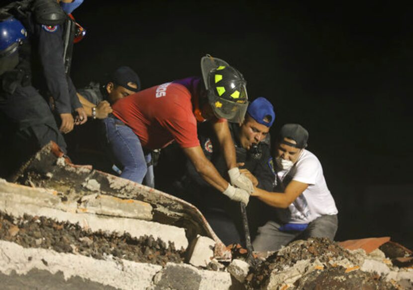 Rescatistas y voluntarios buscan en un edificio derrumbado tras un sismo en el barrio de...