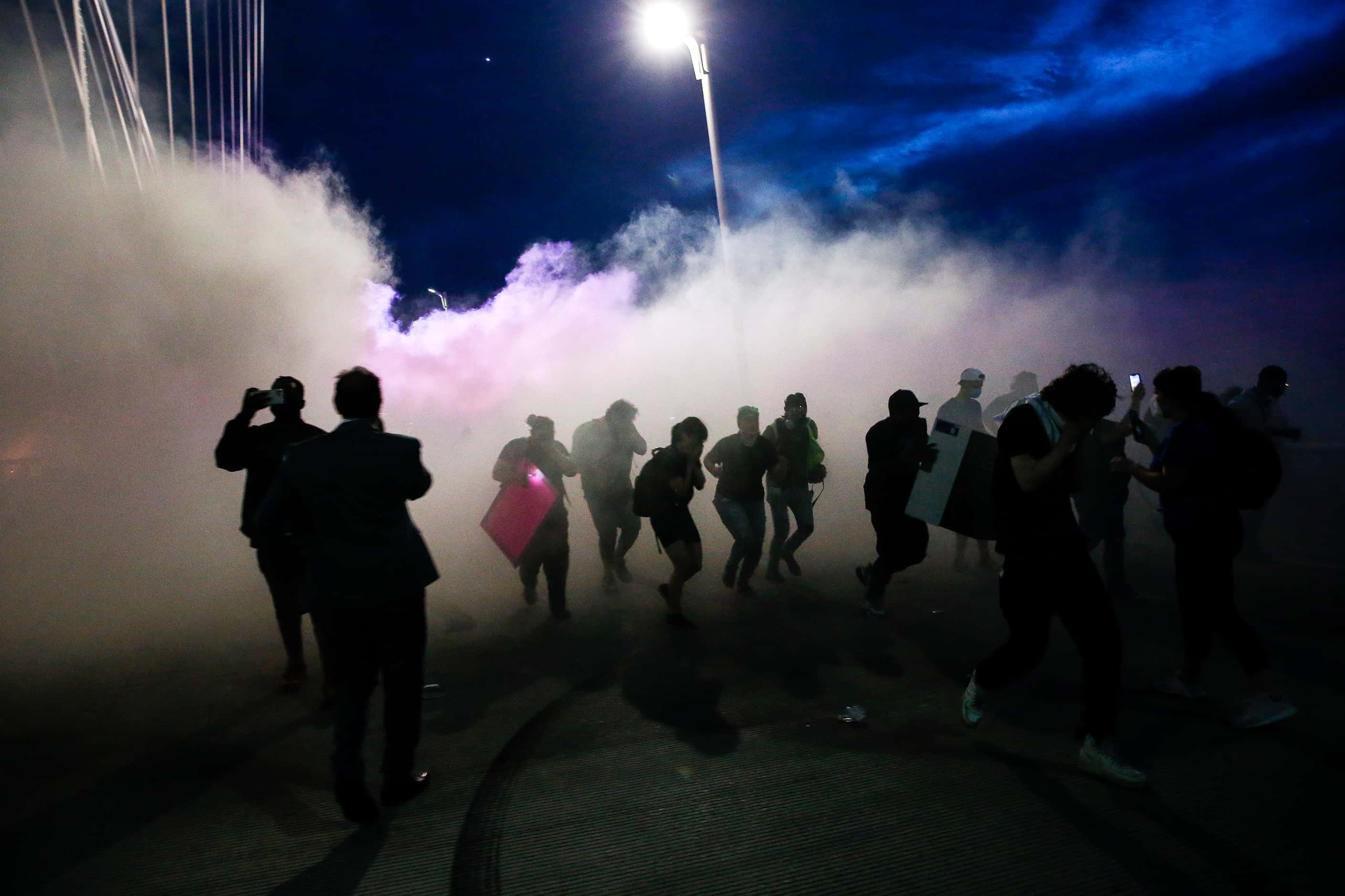 Police deploy smoke bombs and tear gas as they surround protesters who marched onto the...