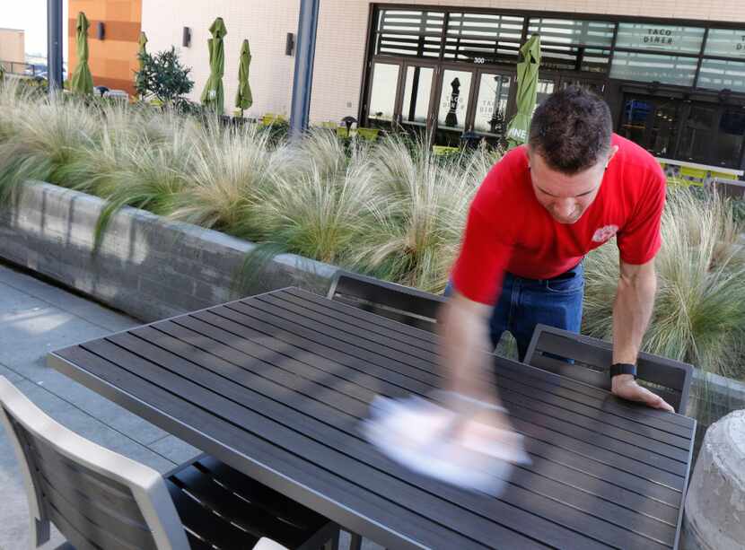 Corey Ahrens, 37, wipes off outdoor tables at Fish City Grill in Richardson, Texas, on...