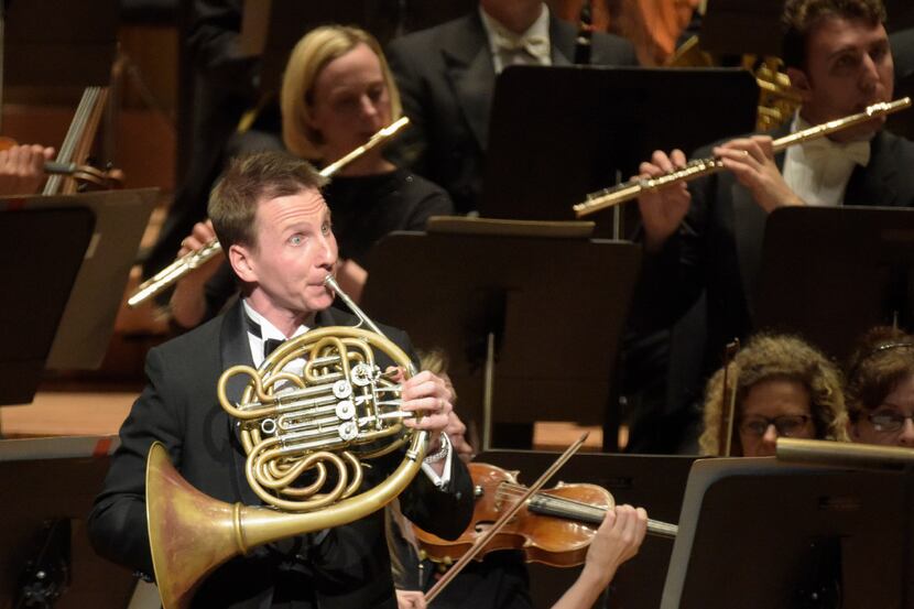 David Cooper plays the French horn as he and other members of the Dallas Symphony Orchestra...