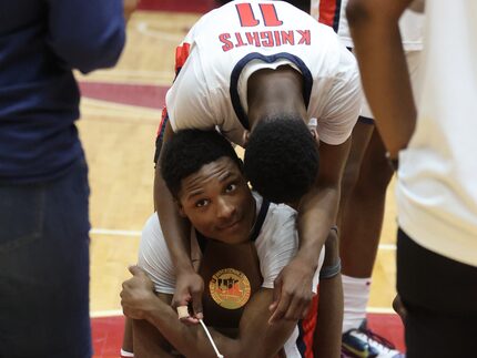 Kimball's Trae Clayton (10) hugs the Championship trophy, as he receives  a hug from...