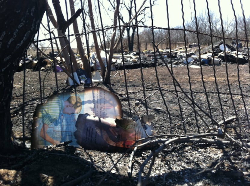 Burned pages of literature and other rubble are all that remain of a woman's house in...