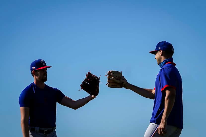 Texas Rangers pitchers Jason Bahr (left) and Brock Burke touch gloves after playing long...
