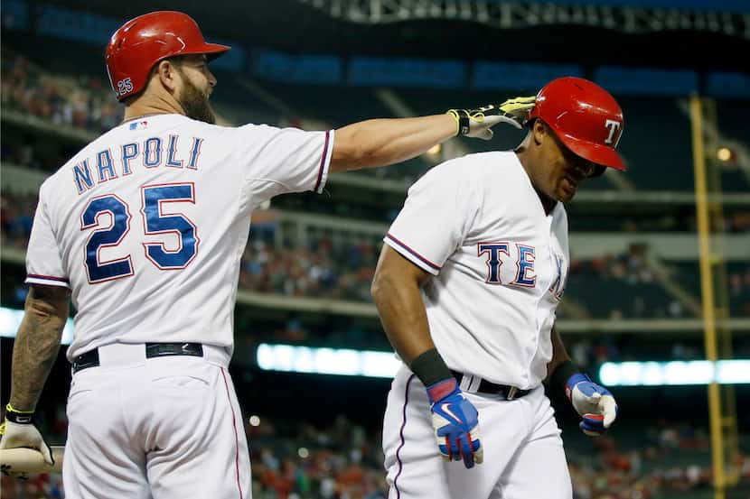 Texas Rangers' Mike Napoli (25) taps Adrian Beltre on the head following his two-run home...