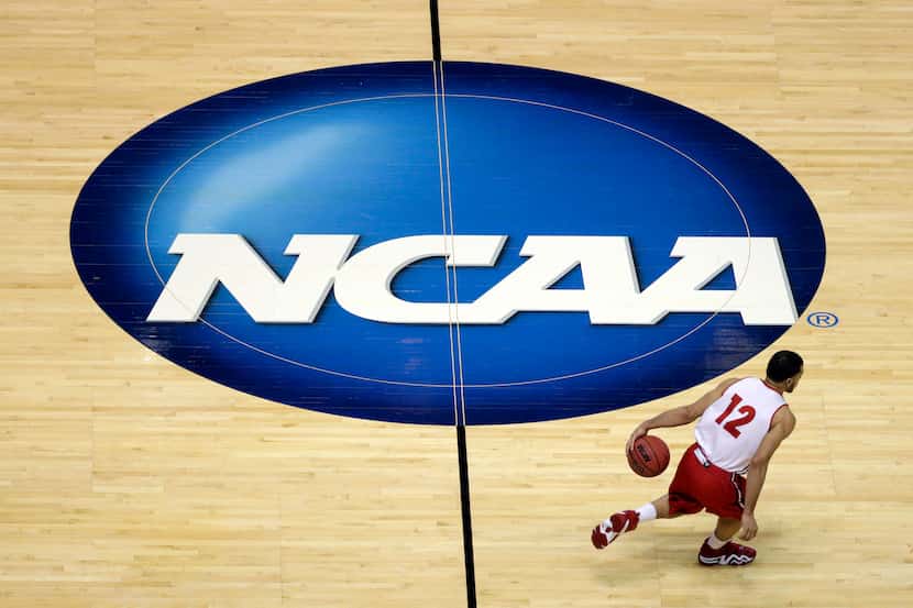 FILE - Wisconsin's Traevon Jackson dribbles past the NCAA logo during practice at the NCAA...