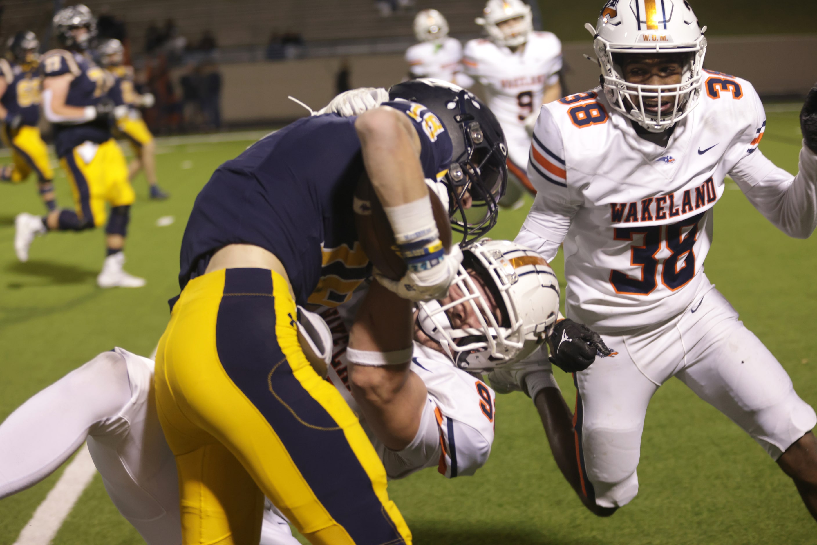 Highland Park's Brandon Lilly gets taken down by Frisco Wakeland defenders in a football...