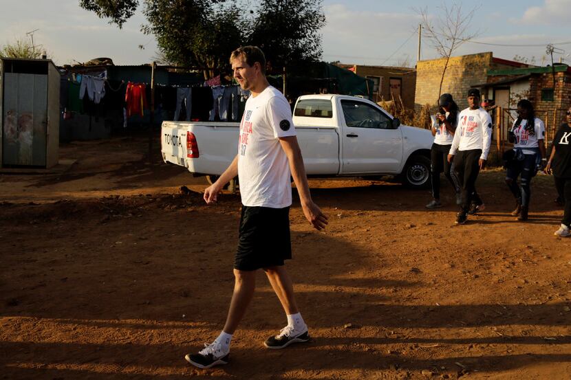 Dirk Nowitzki, of the Dallas Mavericks, walks on a dirt road after helping build a house in...