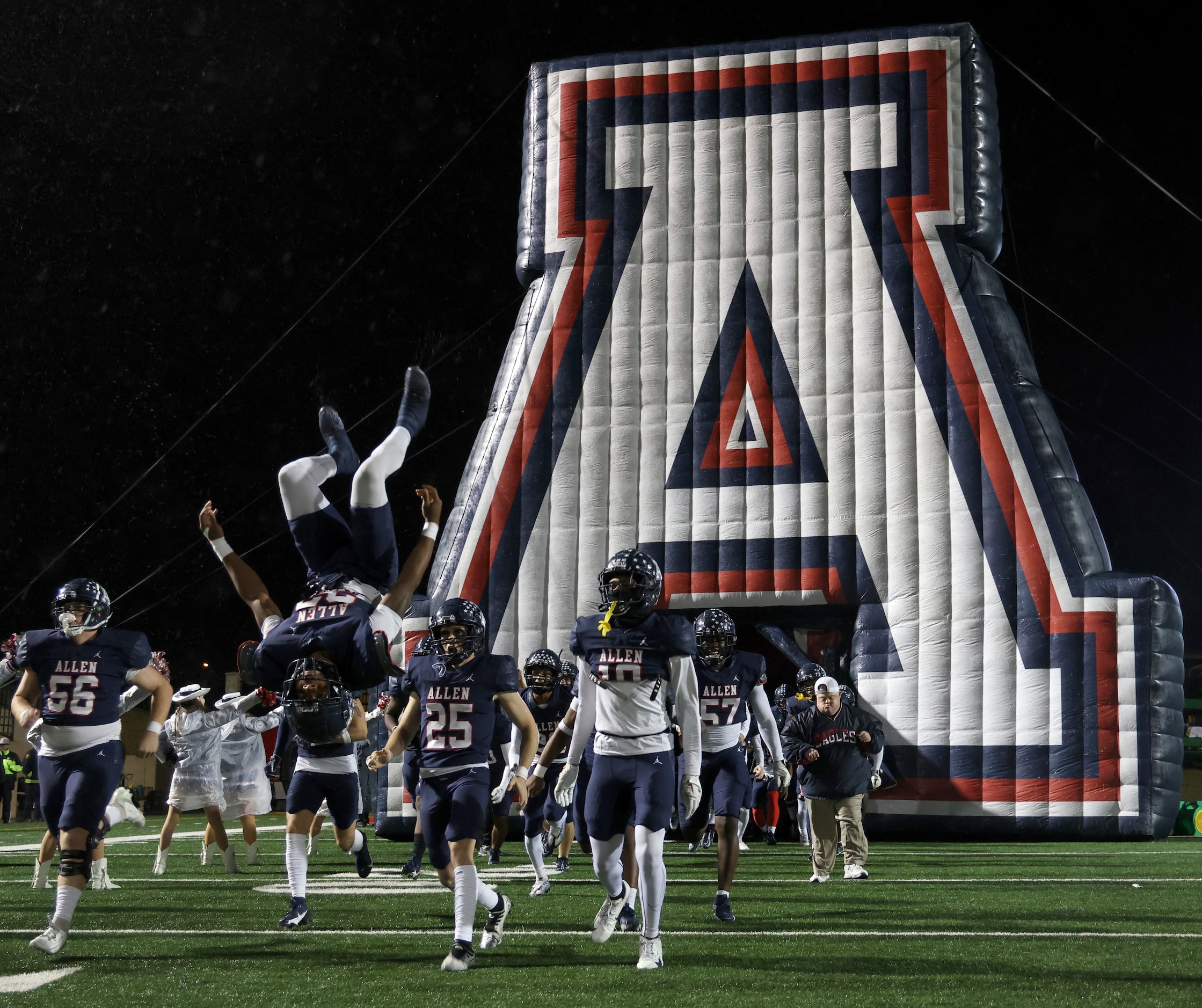 Allen running back Micah Ellis (23) does a flip as he and teammates emerge from the team...