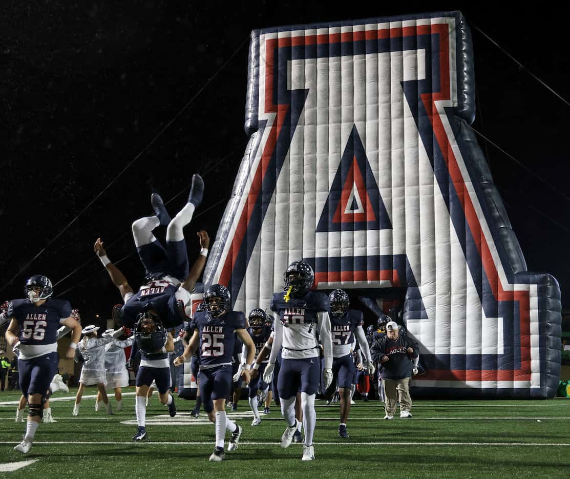 Allen running back Micah Ellis (23) does a flip as he and teammates emerge from the team...