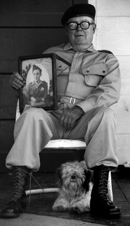 World War II veteran Ernest Raxter holding a 1944 picture of himself.  He is flanked by his...