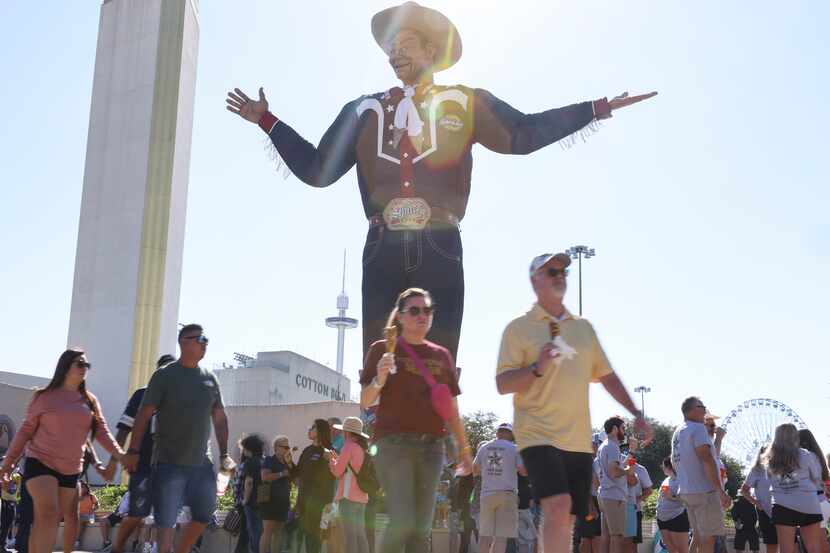 Gente camina junto al gran Big Tex, el viernes 30 de septiembre de 2022 en la Feria Estatal...