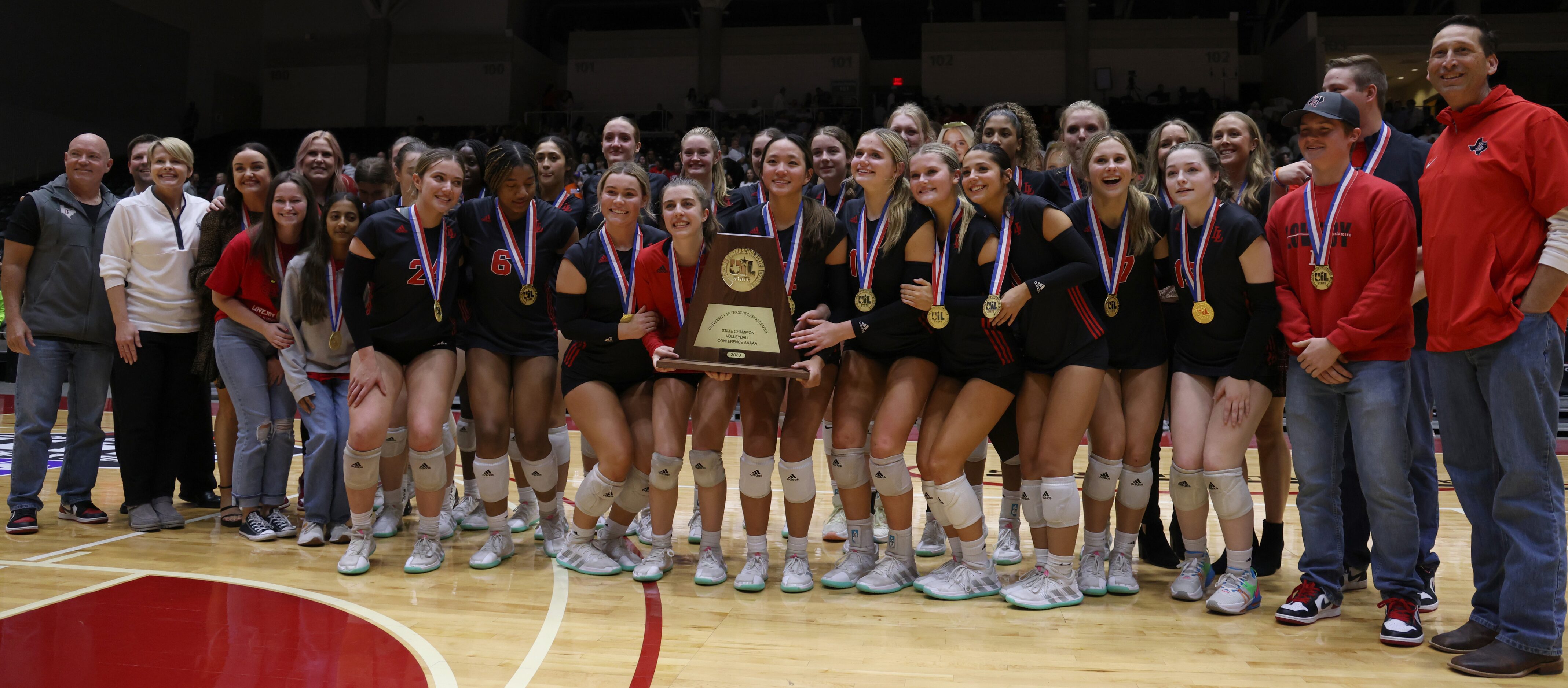 Lucas Lovejoy players and staff members pose with the Class 5A state championship trophy...