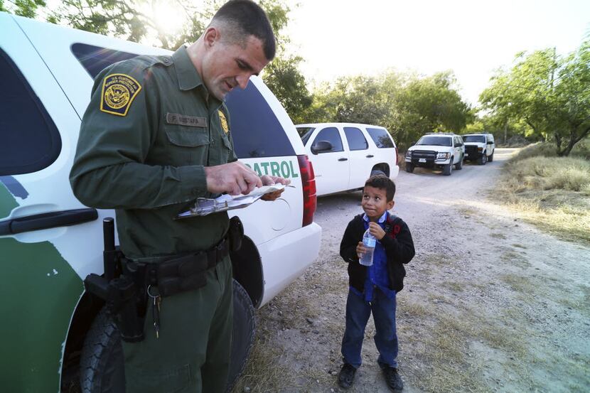 A Border Patrol agent reads the birth certificate of Alejandro, 8. The certificate was the...