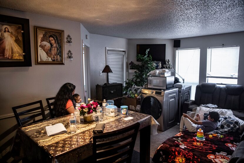 Maria Magarin (left) holds her 6-month-old, Juan Gonzalez Jr., while sitting in the living...