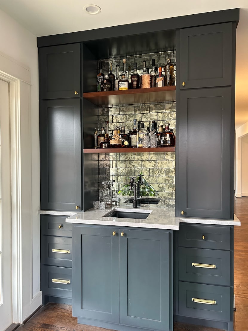 A bar has gray cabinets, gold hardware, and an oil-rubbed faucet.