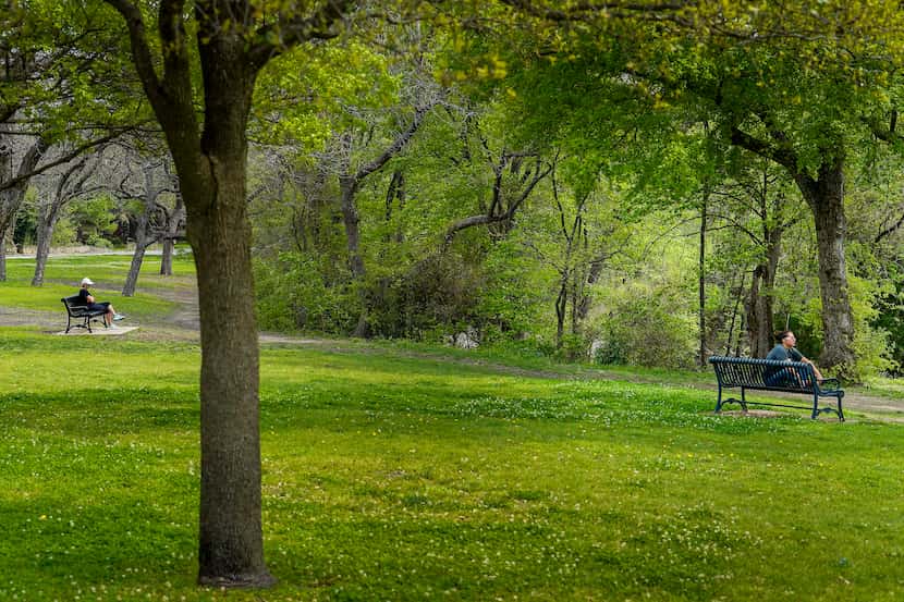 People keep their distance as they sit at separate benches in Prairie Creek Park on Friday,...