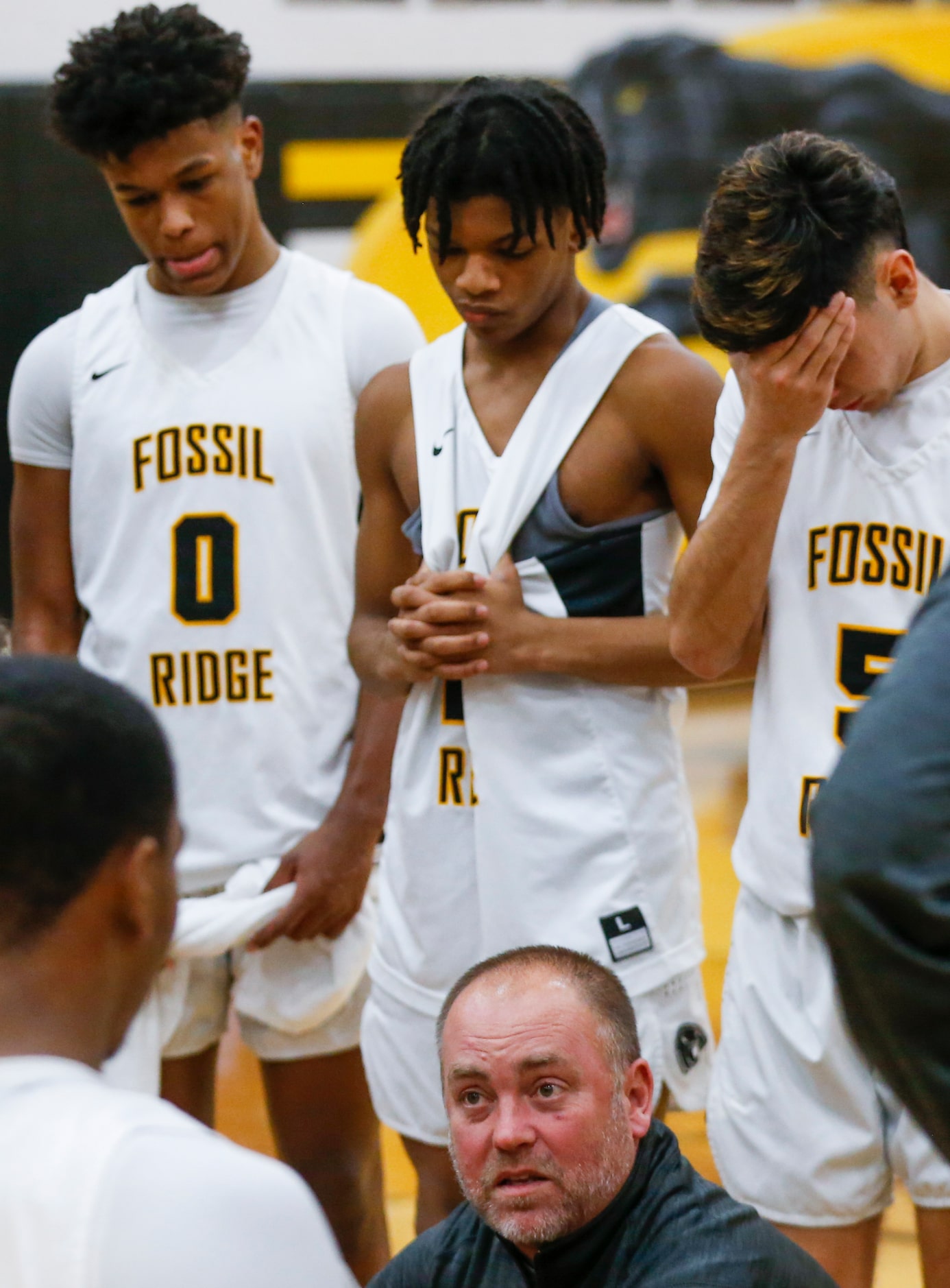 Fossil Ridge High School players listen to their Fossil Ridge High School head coach Zack...