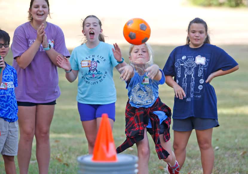 Vanna Vert (second from right), 10, of Plano, throws a ball in effort to knock down a cone...