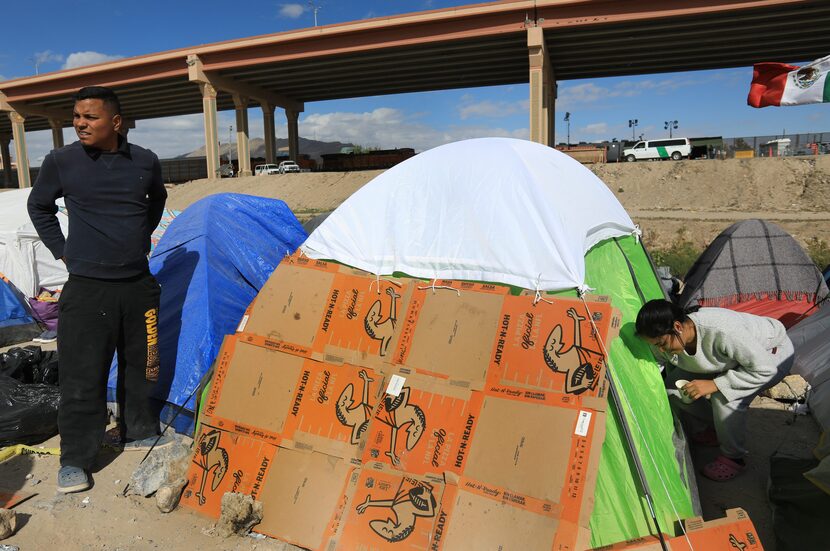 Alexander Sanchez, left, and his wife, Merlyn Mateos, use pizza boxes to protect themselves...