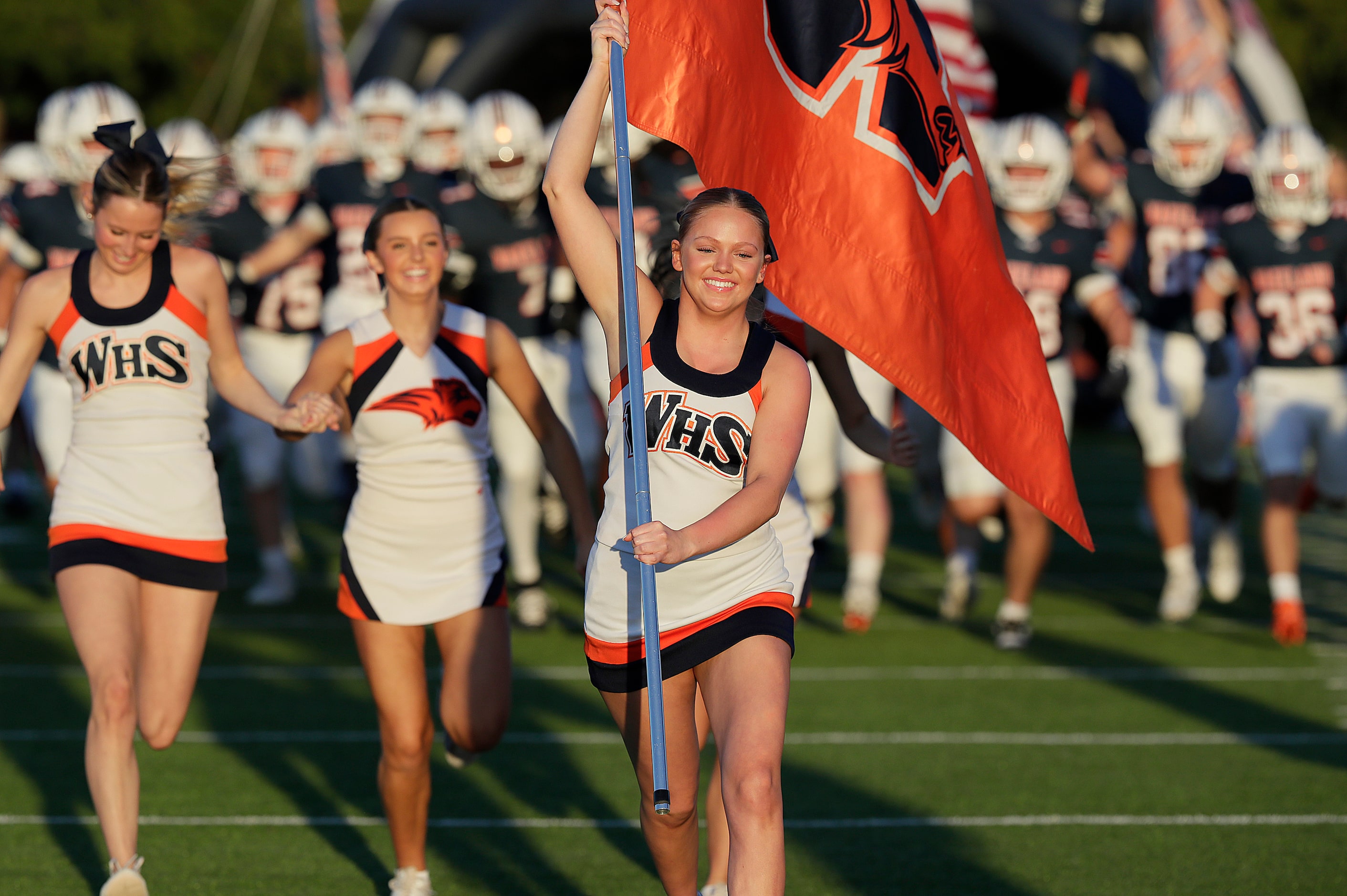 Wakeland High School cheerleader Amber Gleason carries a school flag while leading the team...